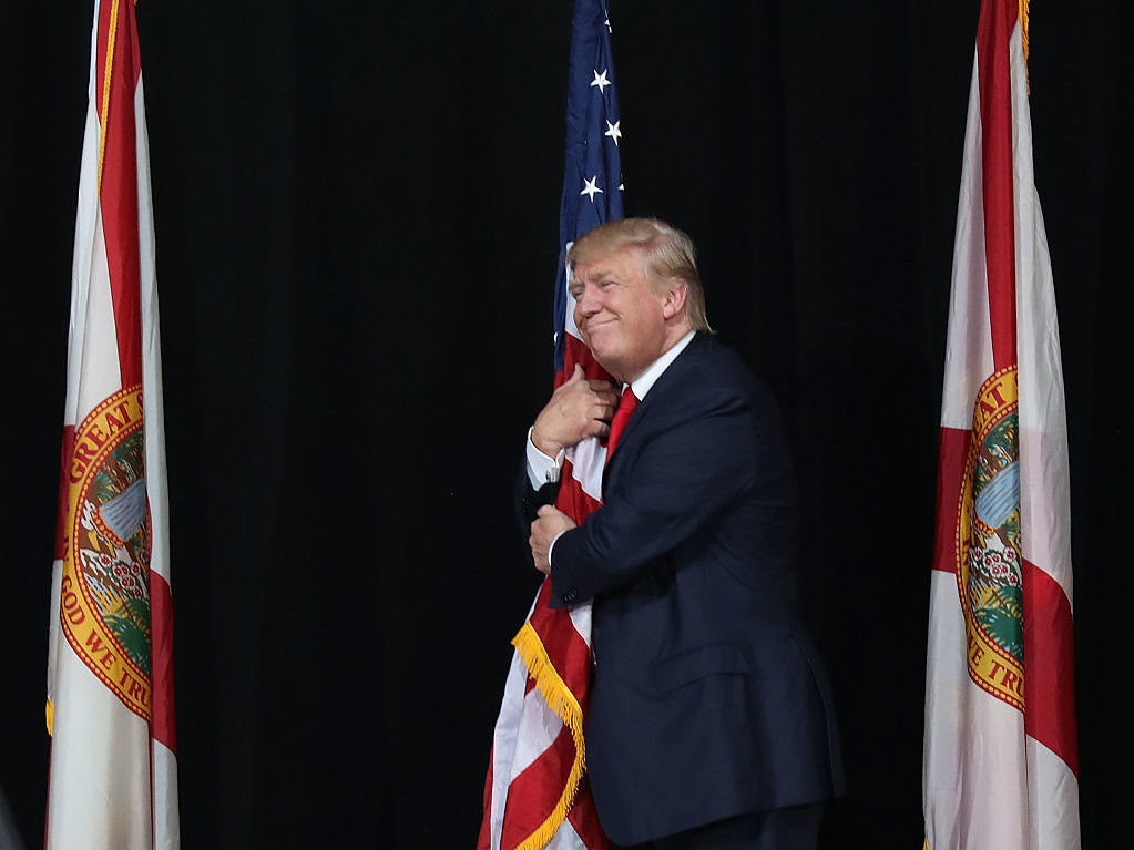 Donald Trump hugs the American flag at a Florida campaign rally in October 2016.